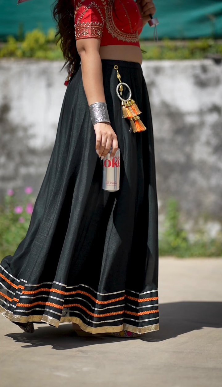 Still from the Coca-Cola film: a woman in a black lehenga and red blouse walking with a Diet Coke can
